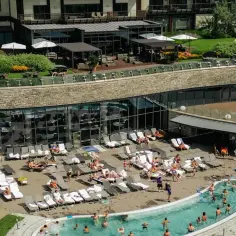 Relaks przy basenie i w jacuzzi to jedne z wielu arłamowskich atrakcji. Widać tu ludzi odpoczywających na leżakach i kąpiących się w wodzie.