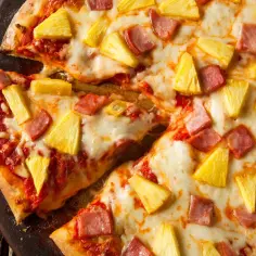 Pyszna pizza z ananasem i szynką, z ciągnącym się serem i sosem pomidorowym. Idealna na szybki obiad.