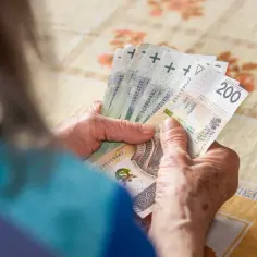 Dłonie starszej osoby liczą banknoty 200 zł. Czy to już czas na 14 emeryturę?