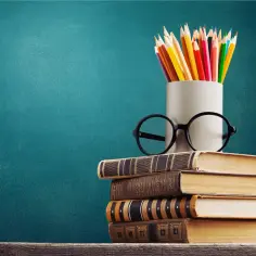 Stos książek, okulary i kolorowe kredki. Nawet z wykształceniem podstawowym można osiągnąć wiele.