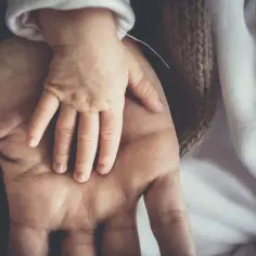 Dłoń dziecka spoczywa na dłoni ojca. To obraz miłości i bezpieczeństwa, jak w tekście "Abba Ojcze".