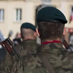 Żołnierze w mundurach moro i zielonych beretach, z bagnetami na karabinach.