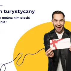 Uśmiechnięty mężczyzna trzyma bon podarunkowy. Czy bon turystyczny można wykorzystać w restauracji na pyszne dania?