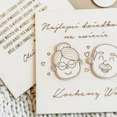 Drewniana kartka na Dzień Babci i Dziadka z rysunkami uśmiechniętych twarzy i napisem "Kochamy Was".