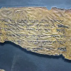 Fragmentary zwoje z Qumran, starożytne teksty pisane hebrajskimi literami na pożółkłym papirusie, ukazujące wieki historii.