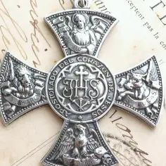Srebrny medalion z krzyżem, na którym widnieją symbole ewangelistów: lew (św. Marek), anioł (św. Mateusz), wół (św. Łukasz) i orzeł (św. Jan).