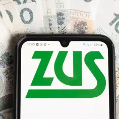 Na ekranie telefonu widnieje logo ZUS. W tle leżą polskie banknoty 100 zł. Czy wiesz, ile wynosi najniższa renta?
