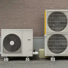 Dwa agregaty czynnika klimatyzacji stoją obok siebie na zewnątrz budynku.