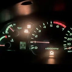 Deska rozdzielcza Toyoty z zapalonymi kontrolkami VSC OFF, VSC TRAC i CHECK ENGINE. Obok wskaźniki paliwa, temperatury i obrotomierza.