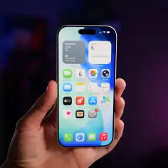Dłoń trzyma iPhone'a z widocznymi ikonami aplikacji, w tym FaceTime. Może to być frustrujące, gdy FaceTime nie działa.