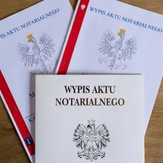 Wypisy aktu notarialnego, kluczowe dla uzyskania kredytu hipotecznego, leżą na drewnianym blacie.
