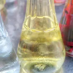 Trzy butelki z różnymi kolorami płynów. Zastanawiasz się, rakija co to? To tradycyjny alkohol.