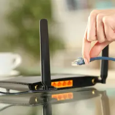 Dłoń podłącza kabel sieciowy do routera TP-Link. Prosty przewodnik, jak ustawić router TP-Link, zaczyna się od tego kroku.