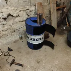 Samodzielnie wykonany piecyk z beczki, z widocznym kominem i drzwiczkami.