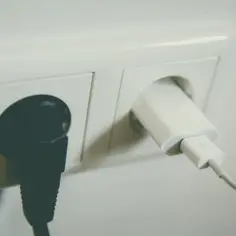 Gniazdko elektryczne z podłączoną czarną wtyczką i białą ładowarką. Różne klasy ochronności zapewniają bezpieczeństwo użytkowania.
