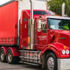 Czerwony, potężny pojazd nienormatywny Kenworth z naczepą, gotowy do transportu.