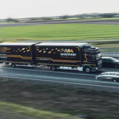 Ciężarówka Marathon International Logistics, z naczepą w barwach firmy, jedzie autostradą. Obok niej mija ją elegancki kabotyn.