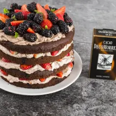 Obłędny tort czekoladowy z mascarpone i owocami, udekorowany jeżynami i truskawkami. Obok stoi opakowanie Cacao DeComorreno.