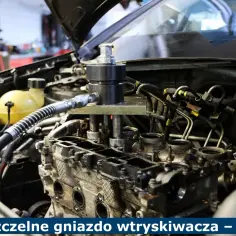 Nieszczelne gniazdo wtryskiwacza w silniku samochodowym, widoczny specjalistyczny przyrząd do naprawy.