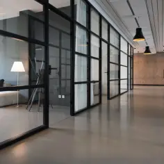 Nowoczesny lokal niemieszkalny z przeszklonymi ścianami, wygodną sofą i designerskimi lampami.
