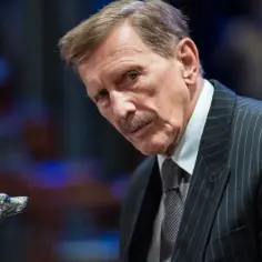 Jan Englert w eleganckim garniturze, z charakterystyczną laską z głową psa. Wiele jego ról w **jan englert filmy** zapisało się w historii polskiego kina.