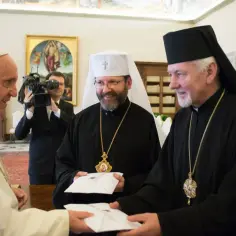 Papież Franciszek wita grekokatolickiego arcybiskupa, wręczając sobie nawzajem koperty.