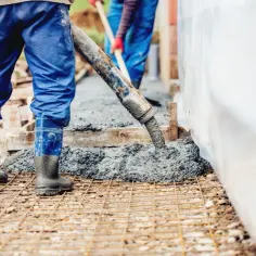 Pracownicy wylewają beton na zbrojenie. Sprawdzamy, jaka jest suchy beton cena 1m3, by zaplanować budowę.