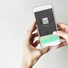 Dłonie trzymają smartfon z ikoną kalendarza i napisem "History". Czas na wyczyść historię przeglądania.