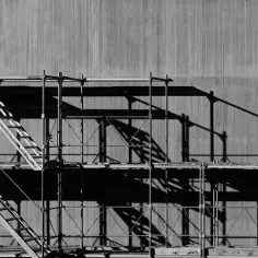 Rusztowanie z drabiną na tle betonowej ściany. Pokazuje, jak ustawić rusztowanie na schodach, tworząc bezpieczne przejście.