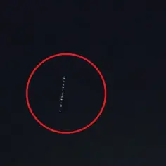 Linia jasnych punktów na ciemnym niebie, przypominająca pociąg satelitów Starlink.