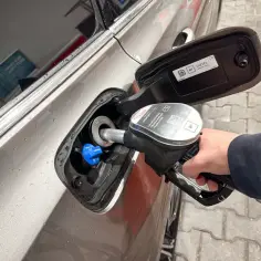 Tankowanie samochodu. Dłoń trzymająca pistolet z dystrybutora, wlewana jest do baku **olej napędowy**.