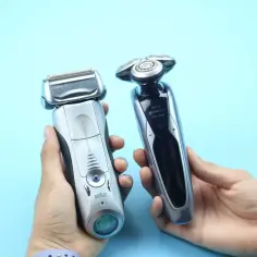 Dwie elektryczne golarki, Braun Series 7 i Philips Norelco Series 9000, prezentowane w dłoniach na jasnoniebieskim tle.