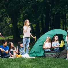 Dzieci świętują dzień małpy, puszczając bańki i bawiąc się przy namiocie w lesie.
