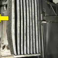 Zabrudzony filtr kabinowy Volvo XC60, wskazany strzałką, czeka na wymianę.