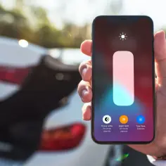 Dłoń trzyma iPhone'a z włączonym trybem Night Shift, gotowego na nocną zmianę.