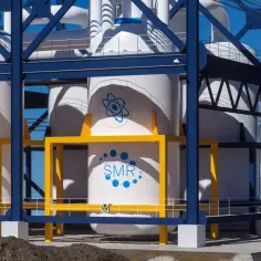 Nowoczesna instalacja SMR z białymi reaktorami i niebieskimi symbolami atomu.