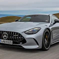 Srebrny Mercedes GT 63 AMG pędzi po krętej drodze, ukazując swoją sportową sylwetkę na tle górskiego krajobrazu.