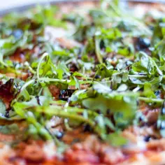 Pyszna pizza z tuńczykiem, rukolą i oliwkami, polana sosem balsamicznym. Idealna na szybki obiad.