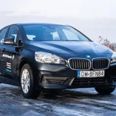 Czarny BMW F45 na oblodzonej drodze, z logo BMW TEAM Długołęka na drzwiach.