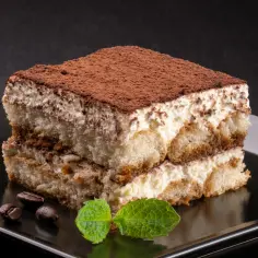 Najprostsze tiramisu, warstwowe ciastko z kremem, biszkoptami i kakao, ozdobione miętą i ziarnami kawy.