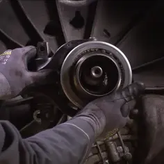 Mechanik w rękawicach wymienia łożysko oporowe w skrzyni biegów.