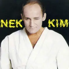 Piotr Fronczewski w białym kimonie, mrugając okiem. W tle napis "FRANEK KIMONO". Ile lat ma Piotr Fronczewski?