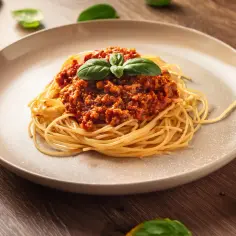 Pyszne spaghetti z sosem bolońskim, ozdobione świeżą bazylią. Idealny wybór, gdy zastanawiasz się, co do spaghetti: bazylia czy oregano.