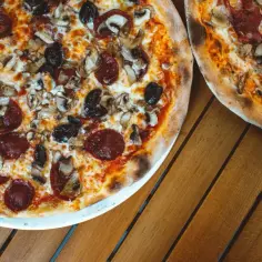 Dwie pizze z salami, pieczarkami i czarnymi oliwkami. Idealne, gdy zastanawiasz się, jakie dodatki do pizzy wybrać.