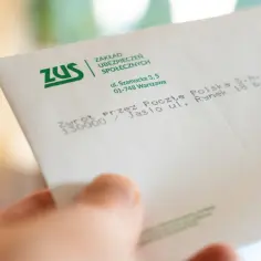 Dłoń trzyma kopertę ZUS. Dokument może dotyczyć waloryzacji emerytury ZUS.