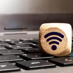 Drewniany sześcian z symbolem Wi-Fi na klawiaturze laptopa. Połączenie bezprzewodowe, czyli wifi direct, jest teraz na wyciągnięcie ręki.