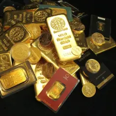 Góra złotych sztabek i monet, jakby darowizna od obcej osoby. Widać napisy "Fine Gold", "1 KILO", "ARGOR-HERAEUS".