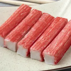 Paluszki surimi na talerzu, gotowe do spożycia. Idealne na lekki posiłek, nawet dla kobiet w ciąży.