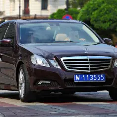 Ciemnobrązowy Mercedes z tablicą W 113555, wskazującą na rejestracje dyplomatyczne.