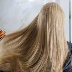 Złota szczotka baicapil delikatnie rozczesuje długie, blond włosy.